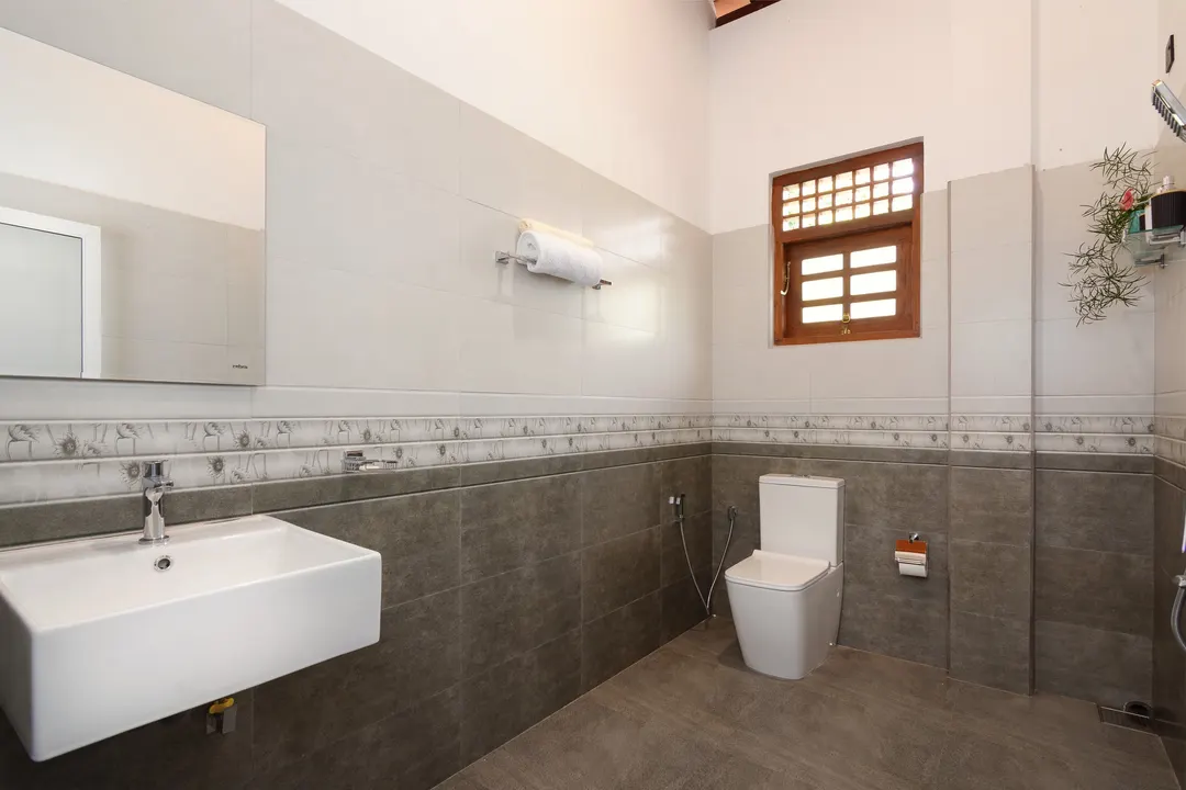 A bathroom in grey and white tiles with a timber window