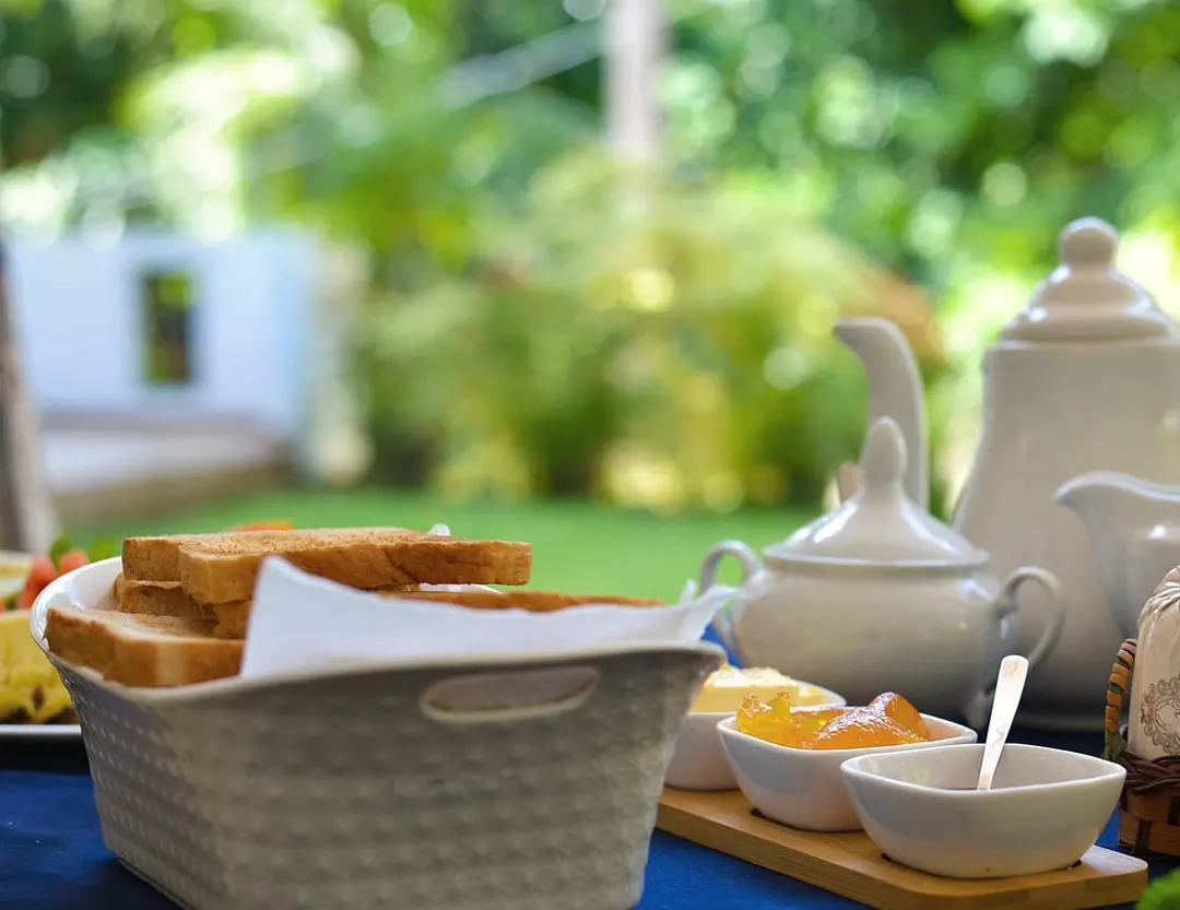Toast, preserves and a pot of tea on the breakfast table, with the garden behind
