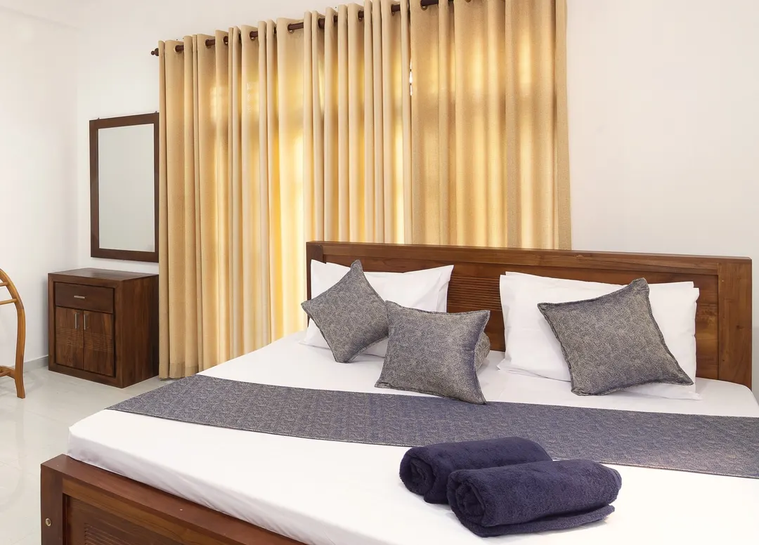 A Deluxe Double Room with a king bed, a teak door and a towel stand