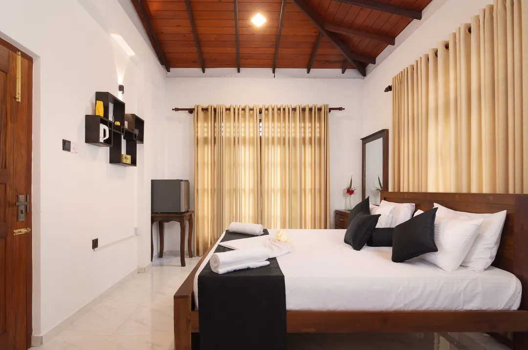 A Deluxe Double with a vaulted timber ceiling and a dark timber bed