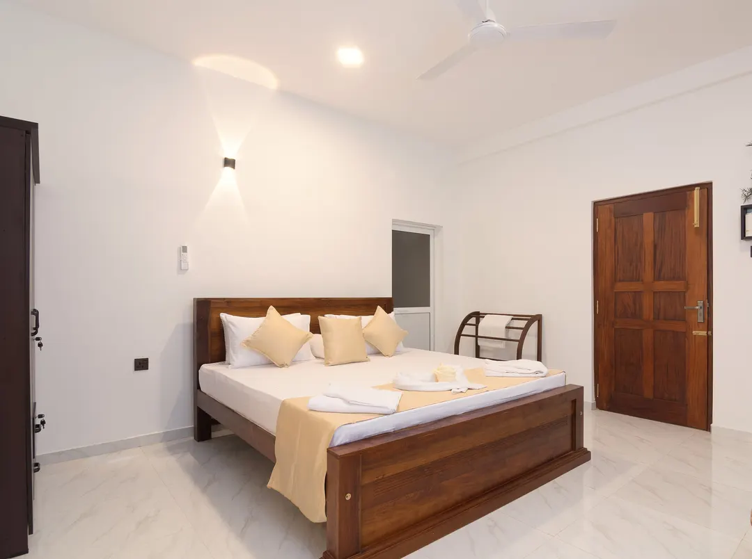 A Deluxe Double with a flat ceiling, soft wall lights and cream cushions