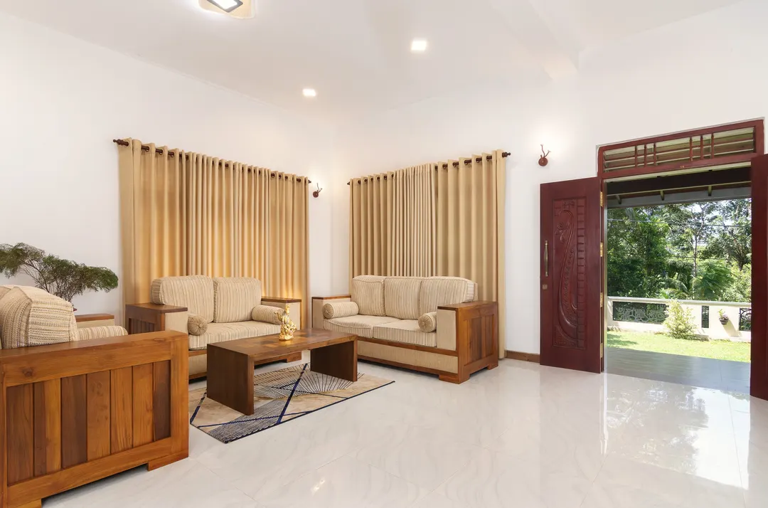 The living room with timber sofas and an open door to the garden