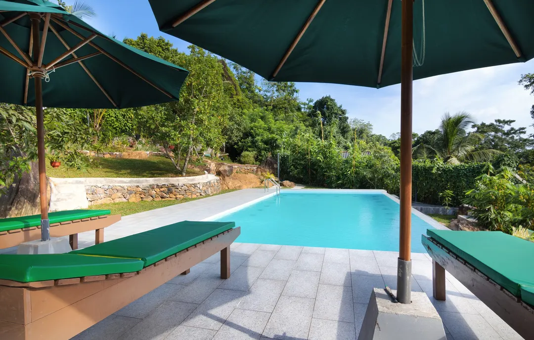 Loungers under green umbrellas beside the pool