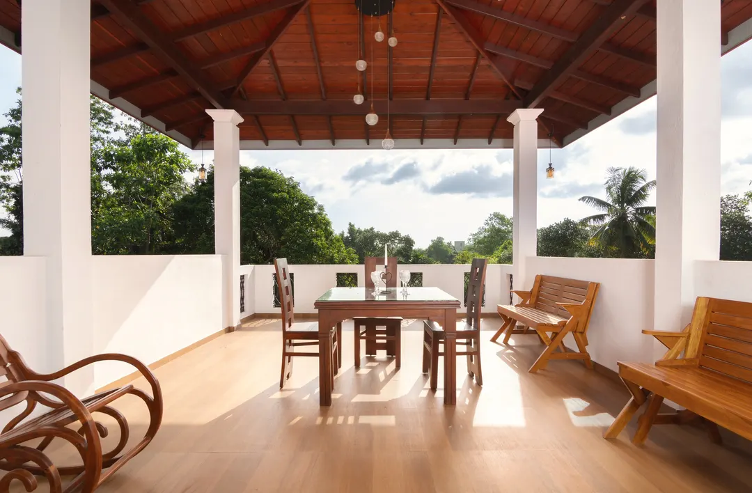 The top-floor terrace by day, with a long timber table and rocking chairs looking out over the trees