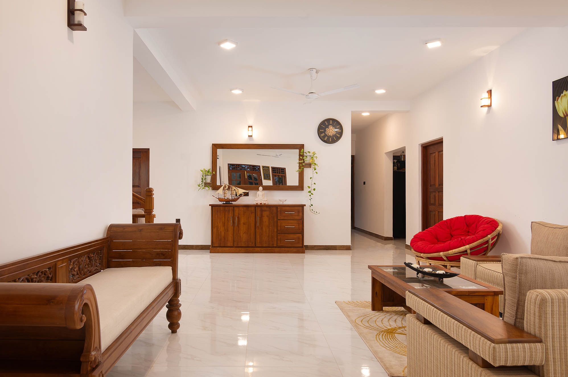 Tranquil Escape Hikkaduwa: Spacious living area featuring traditional wooden furniture, red papasan chair, sleek sideboard with mirror, and polished marble floors, blending modern comfort with Sri Lankan charm