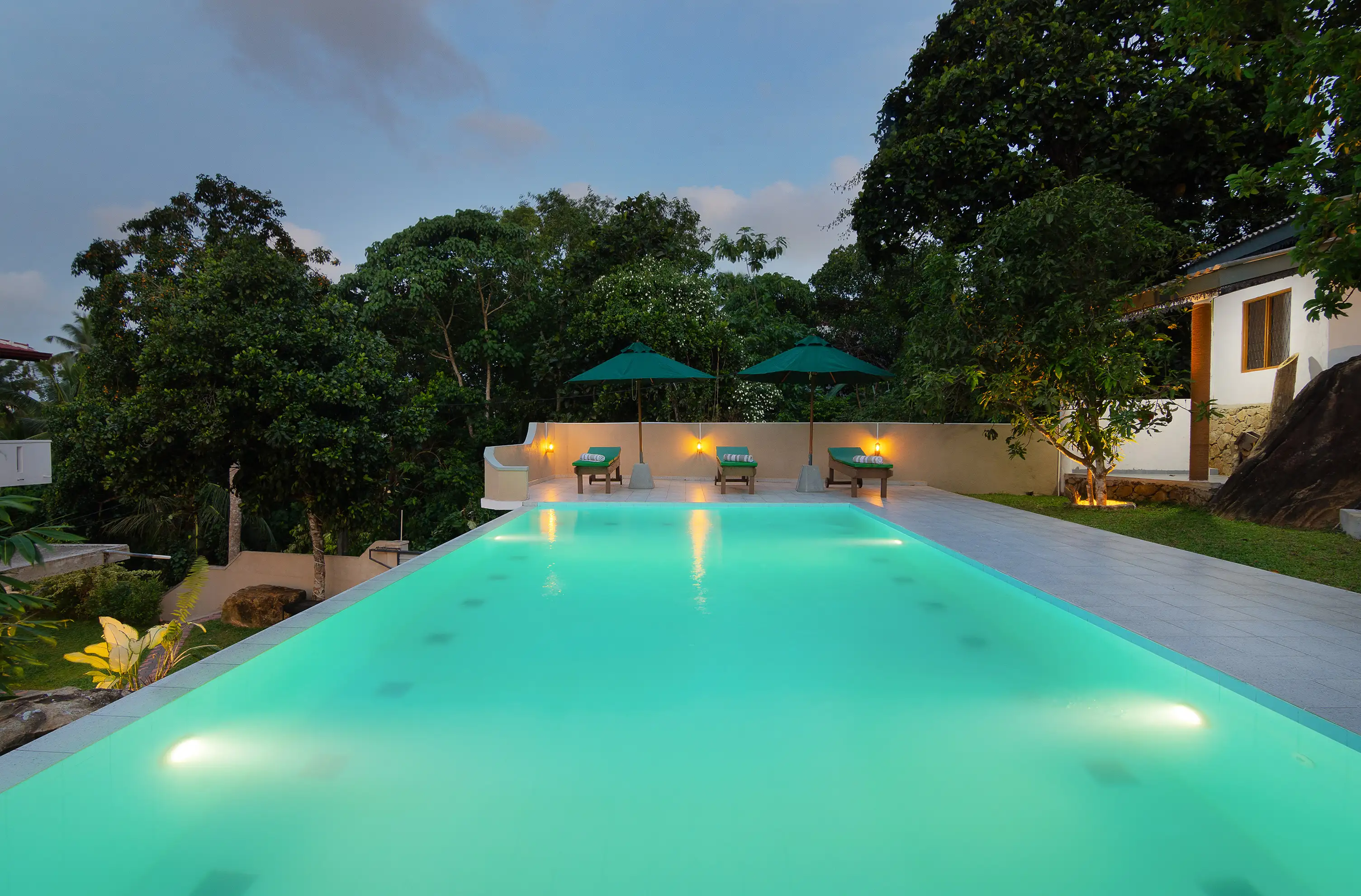 Luxurious outdoor infinity pool surrounded by lush greenery at Tranquil Escape Villa in Hikkaduwa, Sri Lanka, offering a serene and private swimming experience with comfortable lounge chairs and umbrellas for relaxation